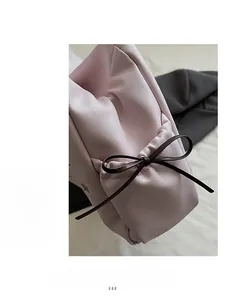 Detail of a pink tote bag showing the side bow decoration and soft textured faux leather