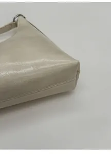 Close-up of cream leather hobo bag showing wide bottom structure and silver metal ring
