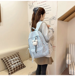 Close-up of light blue backpack with floral texture and white plush bear charm