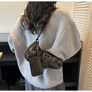 Detail of vintage motorcycle style black leather shoulder bag with metallic buckle straps