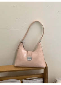Detailed close-up of light pink minimalist underarm bag with silver buckle and grainy texture