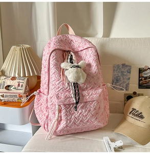 Detail of pink bubble texture backpack featuring a plush bunny charm and tassel decoration