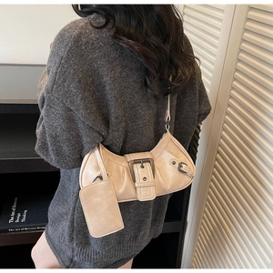 Detail of light beige pleated hobo bag featuring large metal buckle and detachable card holder