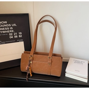 Detail of vintage brown leather handbag with wooden bead tassel and ZHONMA logo
