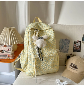 Detailed view of yellow floral quilted backpack with a cute white puppy plush charm