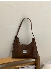 Close-up of retro brown leather shoulder bag with textured finish and metal buckle