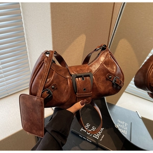 Macro detail of dark reddish brown pleated leather texture and large silver buckle hardware