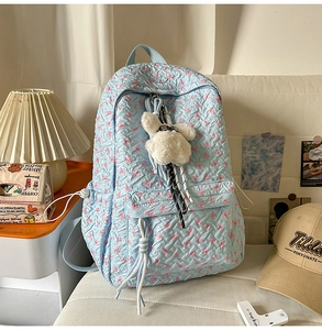 Detail of light blue quilted backpack with pink bow prints and cute bunny keychain
