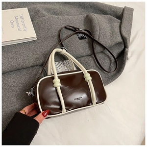 Gros plan du sac Boston marron avec bordures blanches et détails de couture fine