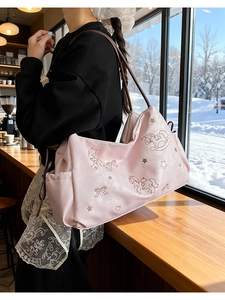 Close-up of pink tote bag featuring cute rocking horse patterns and brown shoulder straps