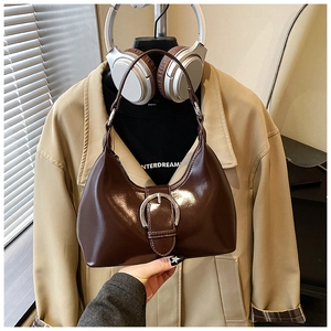 Détail d'un sac sous les aisselles en cuir marron brillant avec boucle argentée