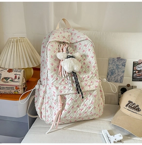 Close-up of beige backpack with pink bow embroidery and cute plush rabbit charm