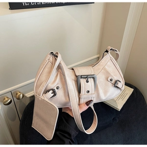 Detail of cream vintage motorcycle style shoulder bag with metallic buckles and mini pouch