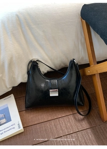 Detail of black leather dumpling bag featuring vintage texture and silver metallic buckle