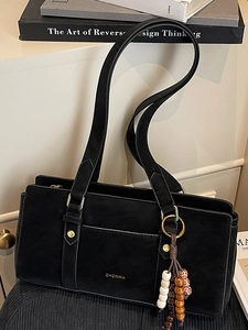 Minimalist black suede shoulder bag with golden hardware and vintage tassel charm