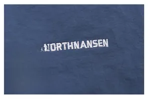 Detail shot of embroidered NORTHNANSEN logo on navy blue woven fabric of backpack