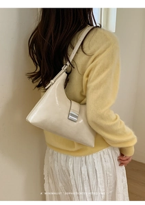 Detail of a creamy beige retro hobo bag with glossy finish and square metal clasp closure