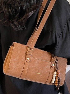Vintage brown leather underarm bag with decorative wooden beads and gold logo detail