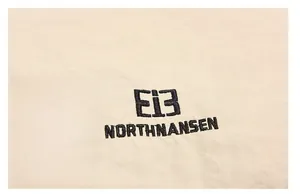 Detailed close-up of beige waterproof fabric with black embroidered brand logo and lettering