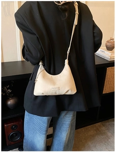 Dettaglio di una borsa hobo in pelle color crema con ciondolo a stella sul modello