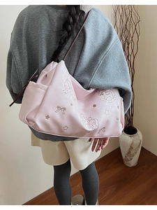 Detailed embroidery of rocking horse and bow motifs on a pink faux leather tote bag