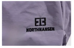 Detailed close-up of purple waterproof fabric with high-quality black embroidery logo
