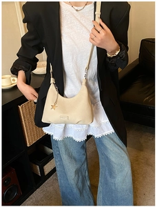 Dettaglio della borsa hobo beige con texture litchi e ciondolo a stella su una modella
