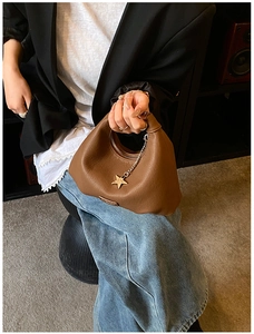 Dettaglio borsa in pelle marrone con ciondolo a stella dorata e design hobo a semicerchio