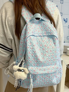 Quilted light blue backpack with pink floral bow patterns and a plush puppy pendant
