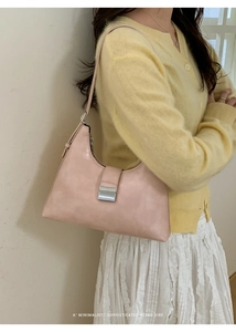 Detail of light pink leather handbag with silver metal buckle on a yellow cardigan