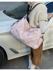 Detail of pink PU leather tote featuring embroidered horse and star patterns with side drawstrings