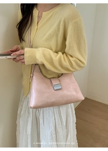 Close-up of minimalist retro pink leather underarm bag with silver metallic clasp detail