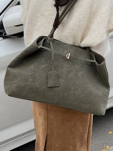 Sac fourre-tout vintage en daim vert olive avec boucle dorée porté dans un décor urbain
