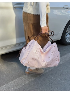 Detail of light pink tote bag with rocking horse print and brown slim handles on a model