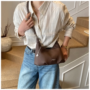 Dettaglio borsa a mezzaluna in pelle marrone scuro con catena a stella e logo in metallo