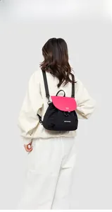 Detail view of the black and pink contrast backpack worn by a model in sports outfit