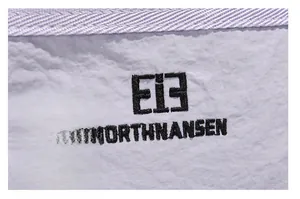 Detail showing the brand logo embroidery on water-resistant lavender nylon fabric