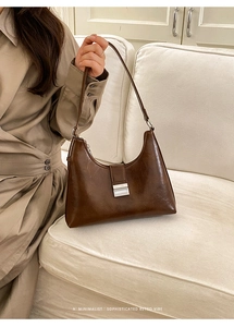 Close-up of minimalist retro brown leather shoulder bag with a silver metallic buckle