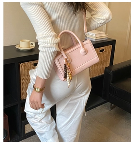 Sac à main en cuir PU mat rose avec perles en bois colorées dans un décor de ville urbain