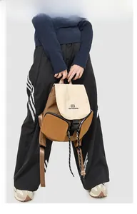 Detail view of the side zipper pocket and adjustable nylon straps on the tan backpack