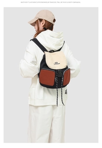 Detail view of the multi-pocket patchwork backpack worn by a model against white background