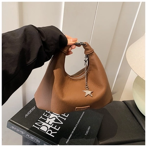 Dettaglio borsa hobo in pelle marrone con ciondolo a stella d'argento e manico metallico