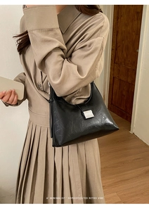 Detail of retro pleated leather texture and silver buckle on black underarm bag
