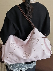 Pink faux leather tote bag with embroidery shown on shoulder from a back view