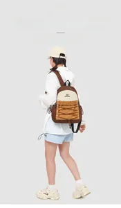 Rear view of a model wearing a minimalist beige and brown nylon backpack with drawstring