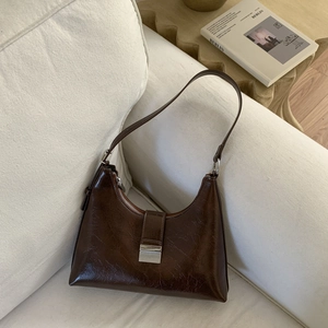 Detailed macro view of dark brown glossy wax leather shoulder bag with silver buckle