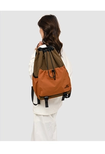 Rear view of model wearing a lightweight drawstring backpack in olive and orange tones