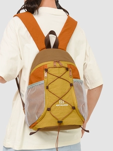 Sac à dos extérieur tricolore jaune et orange avec cordons élastiques porté par le modèle
