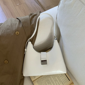 Detailed shot of a white glossy underarm bag with a stylish rectangular metal buckle clasp