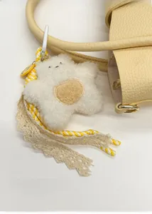 Dettaglio di un ciondolo a stella in peluche bianca con pizzo su una borsa in pelle